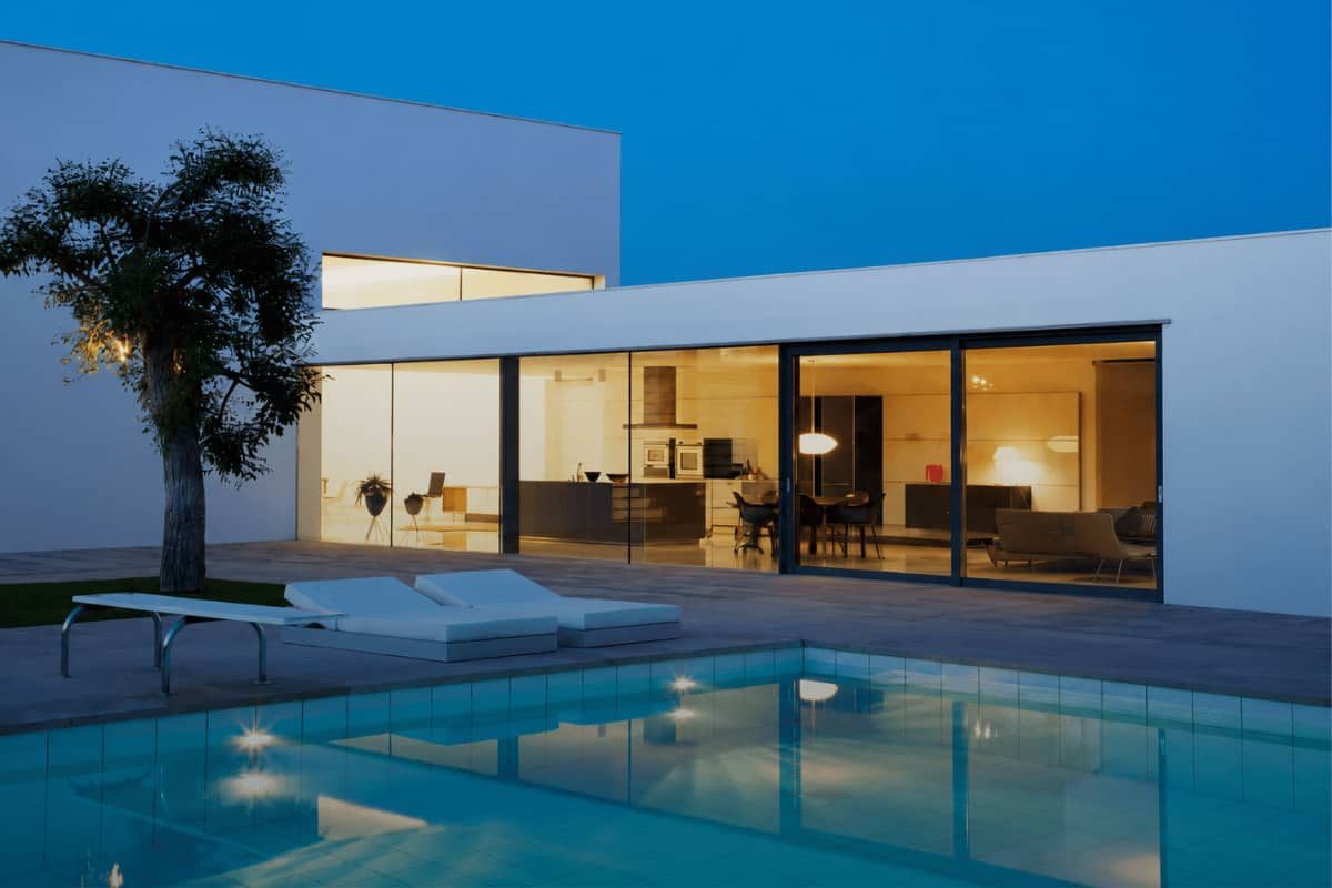 Modern luxury home with swimming pool and glass windows at dusk